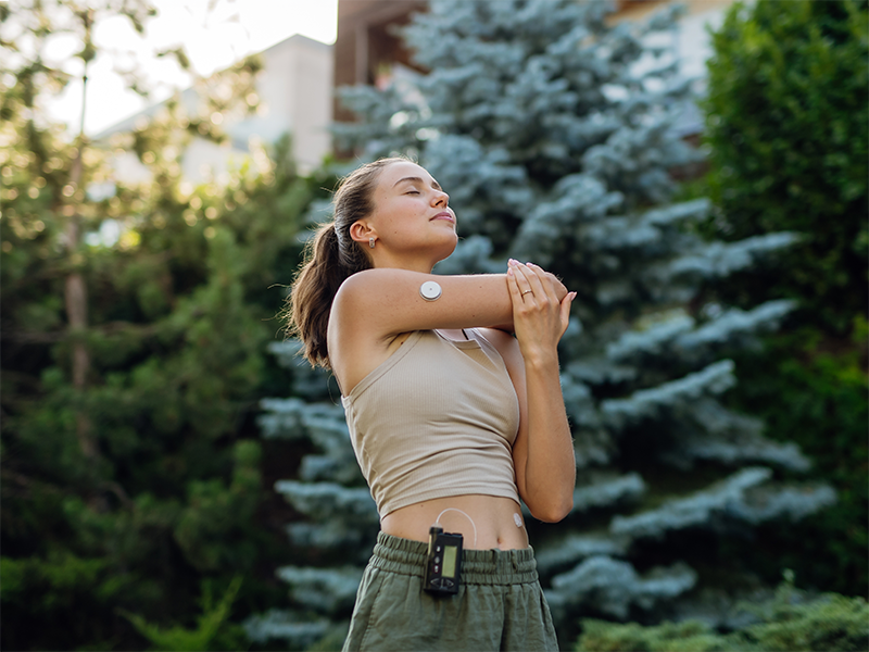 Una mujer joven estira el brazo al aire libre, con un sensor en el brazo.