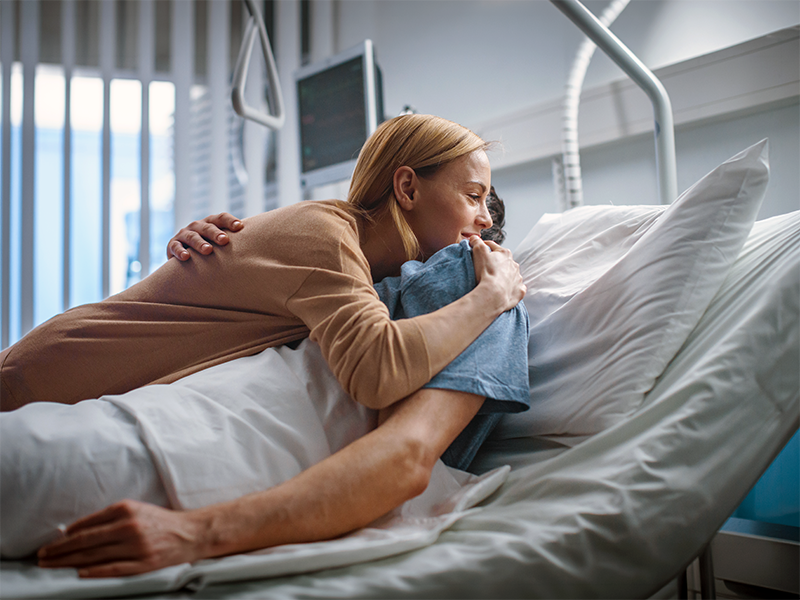 Mujer abraza con cariño a un paciente acostado en una cama de hospital.