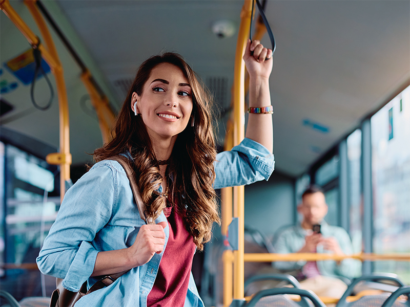 Mujer sonríe de pie en el autobús, camino a su día.